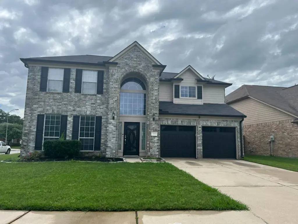 Black garage doors on a two-story brick home