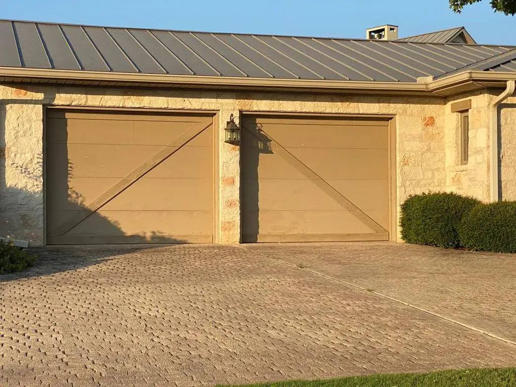 Tan carriage-style garage doors on a stone house