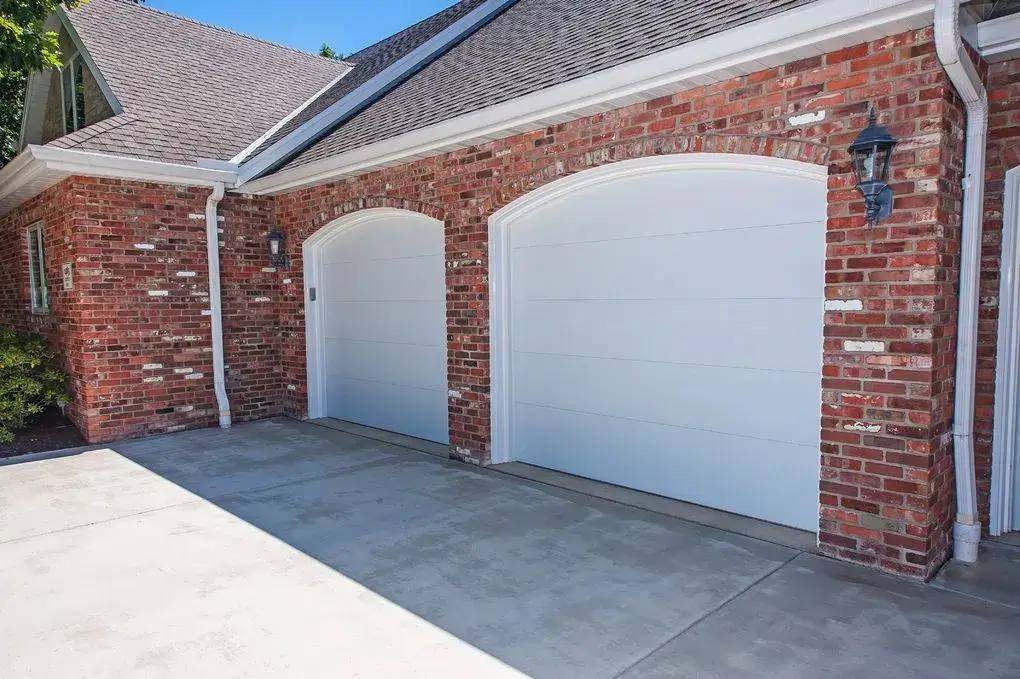 White arched garage doors on a red brick home