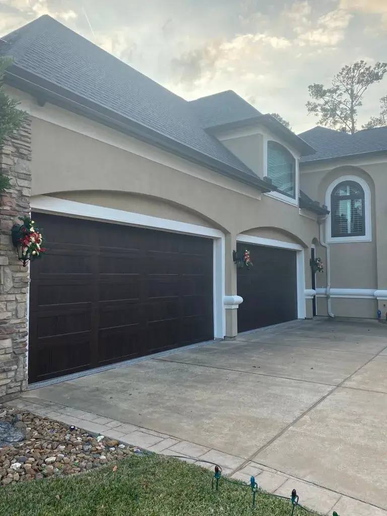 Dark wood-look garage doors under stucco arches