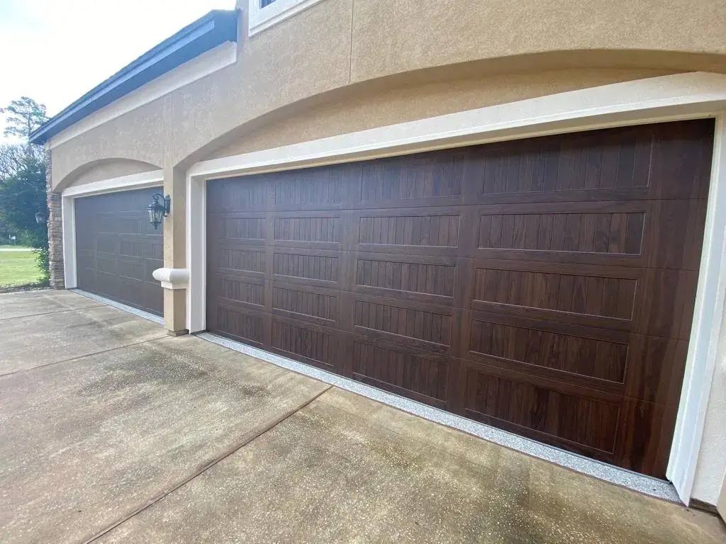 Dark wood-look double garage door on a stucco home